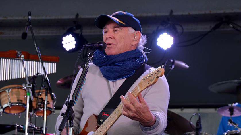 Singer songwriter Jimmy Buffett singing on stage with his coral reefer band.